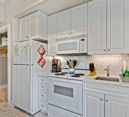 Fully equipped kitchen with crisp white cabinetry, modern appliances, and a sleek subway tile backsplash—ideal for whipping up meals during your 30A stay.