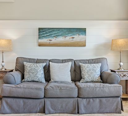 Cozy coastal-style queen sleeper sofa framed by beachy artwork and warm lighting—perfect for relaxing after a day at the beach or accommodating extra guests during your 30A getaway.