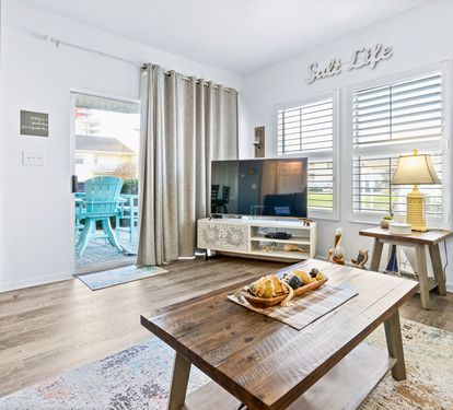 Relax in your bright living space with coastal touches, where morning light filters through plantation shutters and opens to your private patio retreat.