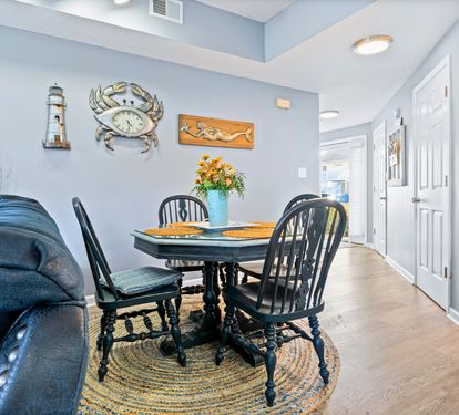 Gather around this charming dining table adorned with coastal touches, where you'll share meals surrounded by nautical art and warm lighting.