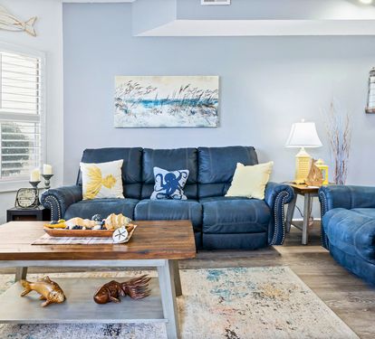 Sink into the coastal-themed living room where plush navy sofas and nautical décor create your perfect seaside retreat.