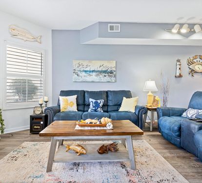 Sink into plush blue sofas in your coastal-themed living room, where nautical artwork and warm lighting create the perfect retreat for relaxing evenings.