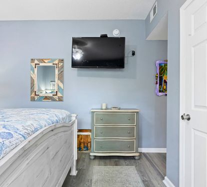 Relax in your serene coastal-themed bedroom with soothing blue walls, comfortable bedding, and your own wall-mounted TV for evening entertainment.