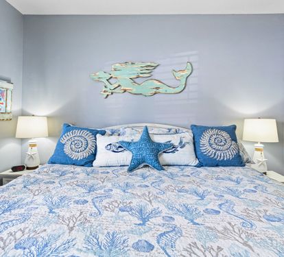 Sink into coastal comfort with ocean-themed bedding and charming mermaid wall art creating your seaside sanctuary.