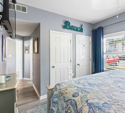 Drift off to peaceful sleep in your beach-themed bedroom with coastal colors and natural light streaming through shuttered windows.