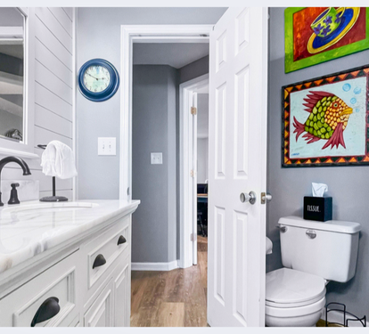 Your stylish bathroom features marble countertops, elegant fixtures, and vibrant coastal artwork creating a fresh, welcoming space.