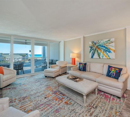 Unwind in your elegant living room where coastal artwork and vibrant rugs create a tropical paradise, while stunning balcony views invite relaxation.