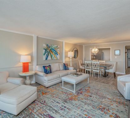 Sink into plush sofas and unwind in your spacious living room, where coastal artwork and pops of coral create a serene retreat.