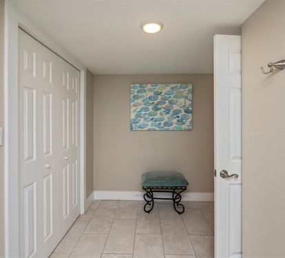 Step into your private retreat where ocean-inspired artwork and a cozy bench create a peaceful transition space before exploring your coastal getaway.