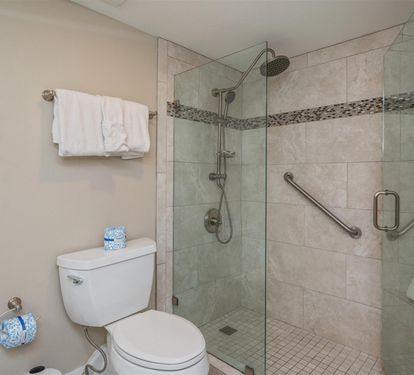 Step into your private spa-like bathroom featuring a spacious glass-enclosed shower with rainfall head and thoughtful accessibility features for ultimate comfort.