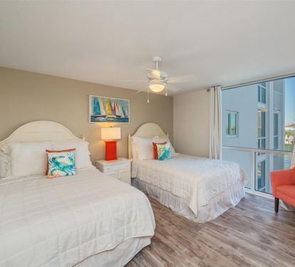 Your cozy bedroom features twin beds with crisp linens, cheerful artwork, and a comfortable chair for relaxing.