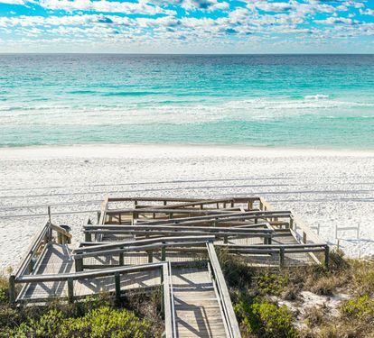 Pristine white sand beach with turquoise waters and wooden boardwalk providing easy access to the shoreline.