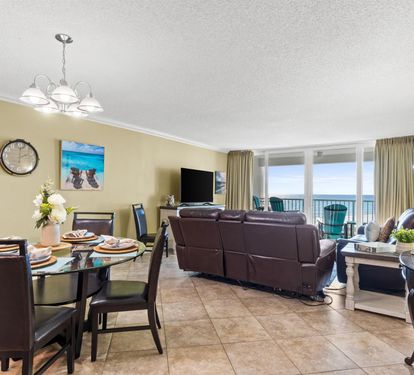 Your open-concept living space flows seamlessly from dining to relaxation, with stunning ocean views through floor-to-ceiling windows creating the perfect coastal retreat.