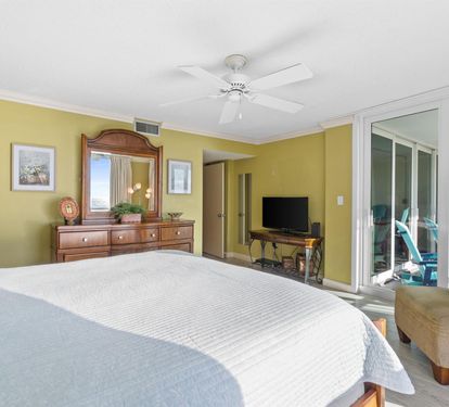 Unwind in your bright bedroom sanctuary with cheerful walls, ceiling fan comfort, and balcony access to ocean breezes.