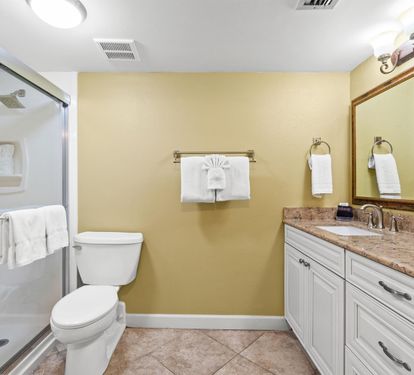 Refresh in your elegant bathroom with marble countertops, glass shower, and thoughtful amenities including fluffy towels.