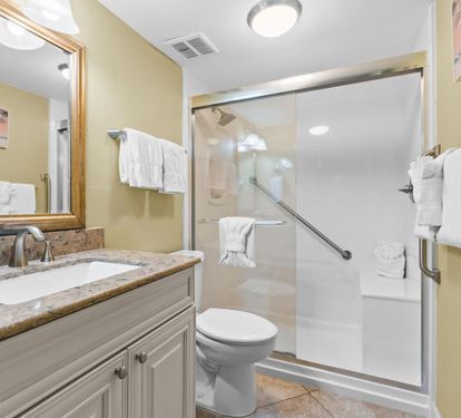 Step into your pristine bathroom featuring a spacious walk-in shower, granite vanity, and fluffy white towels awaiting your arrival.