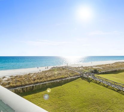 Stunning beachfront vista with pristine white sand, turquoise waters, and coastal walkways stretching along the shoreline.