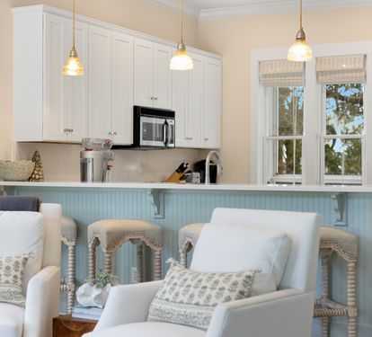 Relax in your bright coastal kitchen featuring white cabinetry, modern appliances, and charming pendant lighting perfect for morning coffee.