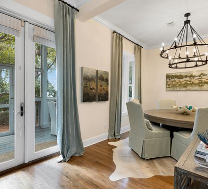 Gather around your elegant dining table where warm light from the wrought-iron chandelier creates the perfect atmosphere for memorable meals together.