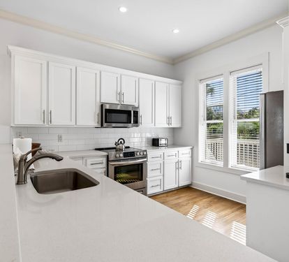 Your modern kitchen awaits with pristine white cabinets, quartz counters, and stainless appliances—perfect for preparing memorable meals during your stay.