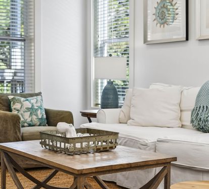 Sink into plush sofas in your bright, airy living room where coastal touches and natural light create the perfect retreat.