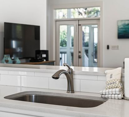 Your bright kitchen island invites cooking adventures with sleek quartz counters, undermount sink, and thoughtful touches like paper towels within easy reach.