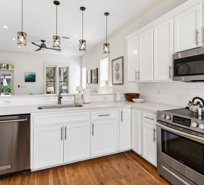 Cook with joy in your bright, modern kitchen featuring pristine white cabinets, gleaming stainless appliances, and stylish pendant lighting overhead.