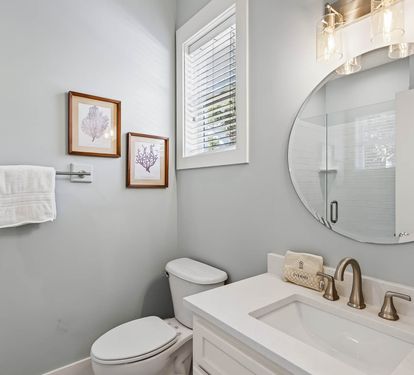 Step into your elegant powder room featuring a quartz vanity, stylish round mirror, and coastal-inspired artwork that creates a spa-like atmosphere.