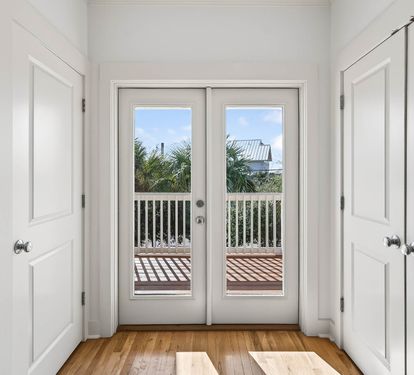 Step through these elegant French doors to your private balcony, where tropical palms and blue skies create the perfect backdrop for morning coffee.