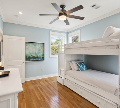 Your kids will love this bright bunk room with calming blue walls, ceiling fan, and TV for cozy bedtime stories.