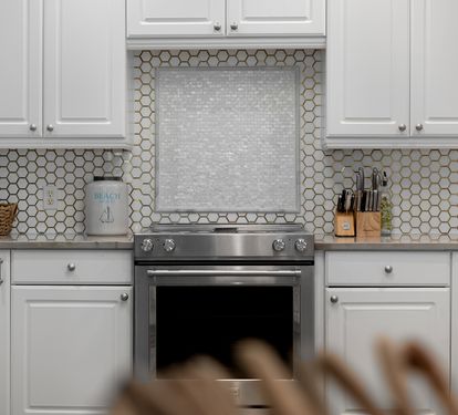 Your gourmet kitchen awaits with pristine white cabinets, stylish hexagonal backsplash, and premium stainless steel appliances ready for culinary adventures.