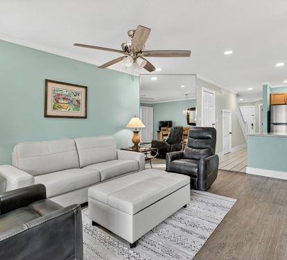 Relax in your spacious living area with comfortable seating, ceiling fan, and open layout that flows seamlessly into the fully equipped kitchen.