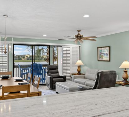 Relax in your spacious living area with comfortable seating, ceiling fan, and stunning waterfront views through sliding glass doors leading to your private balcony.