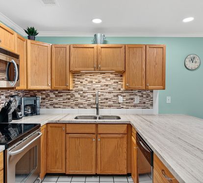 Your fully equipped kitchen features modern appliances, granite countertops, and warm wood cabinetry - perfect for preparing meals during your stay.