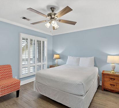 Relax in your peaceful bedroom with soothing blue walls, comfortable seating, and natural light from plantation shutters creating the perfect retreat for rest.
