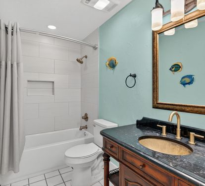 Refresh in your charming nautical bathroom with ocean-inspired décor, marble countertops, and a relaxing tub-shower combo for your coastal getaway.