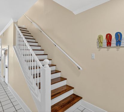 Welcoming interior staircase with coastal charm - colorful flip-flops displayed on the wall add a playful beach house touch to your stay.