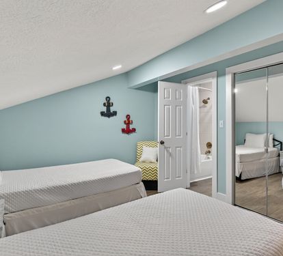 Relax in this charming nautical-themed bedroom featuring twin beds with crisp linens, coastal décor, and a convenient ensuite bathroom for your comfort.