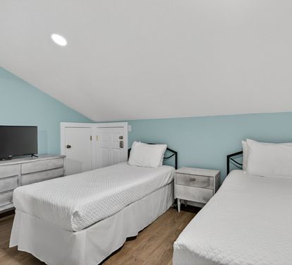 Your peaceful twin bedroom features comfortable beds with crisp white linens, modern furnishings, and a flat-screen TV for your entertainment.