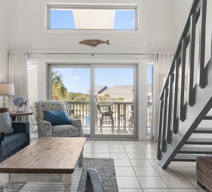 Relax in your bright coastal living room with ocean-themed touches and private balcony access.