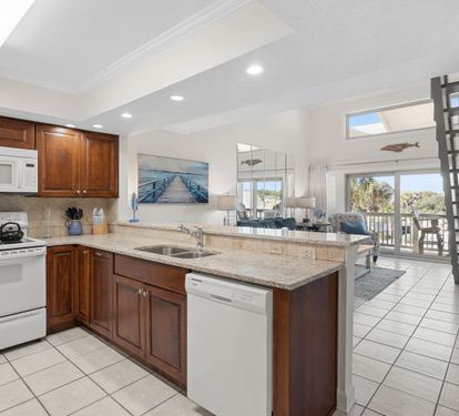 Your spacious kitchen boasts granite counters, rich wood cabinets, and modern appliances perfect for preparing coastal meals together.
