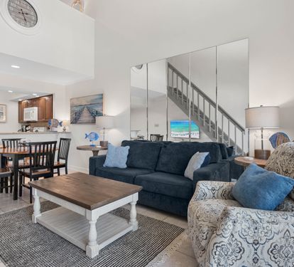 Your open-concept living space features coastal blues and comfortable seating, perfect for gathering with family after beach days.