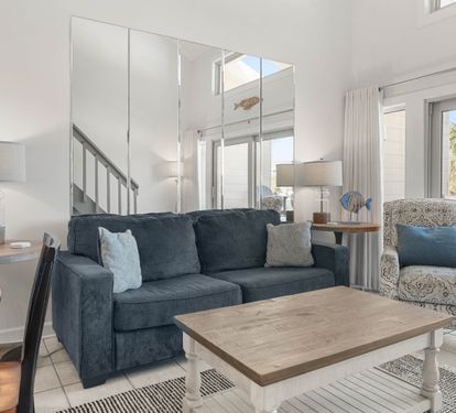 Sink into coastal comfort in your bright living space with stylish furnishings and gentle natural light streaming through large windows.