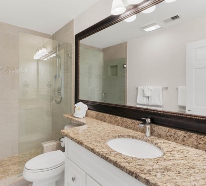 Step into your elegant bathroom featuring granite countertops, a spacious glass-enclosed shower, and thoughtfully placed amenities for your comfort.