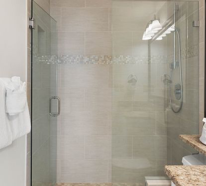 Step into your spa-like bathroom featuring a spacious glass shower with elegant mosaic tile details and plush towels ready for your stay.