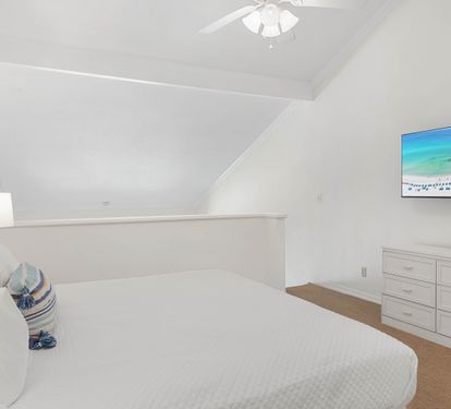 Drift off in your peaceful attic bedroom, where crisp white linens and coastal artwork create a serene seaside retreat.