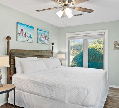 Relax in the inviting primary bedroom featuring a comfortable bed, calming coastal décor, and a peaceful retreat designed for restful nights after beach adventures.