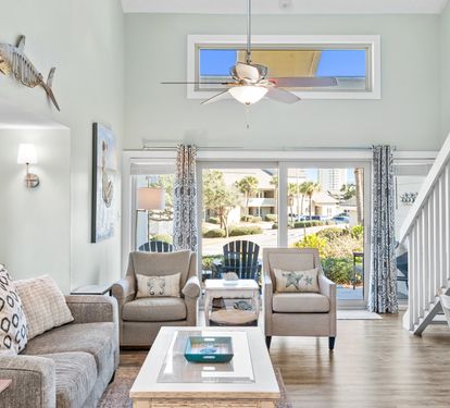 Bright and welcoming living space with soaring ceilings, abundant natural light, and relaxing coastal décor — perfect for unwinding after a fun-filled day at the beach.
