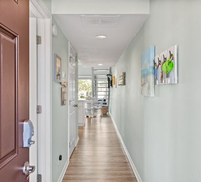 Welcoming entry hallway leads into a bright, open coastal living space with updated finishes, airy décor, and plenty of room to relax during your beach getaway.