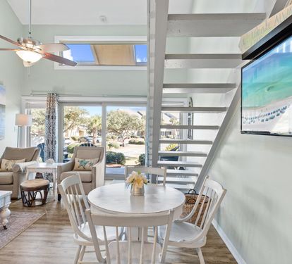 Bright coastal dining area with an open-concept layout, soaring ceilings, and abundant natural light — perfect for gathering, dining, and relaxing after a day at the beach.